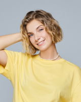 Professional headshot of Alexandra Baptizmanskaya smiling and wearing a light yellow shirt in front of a white background.